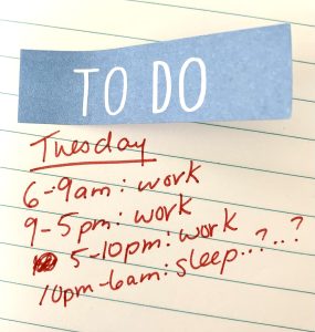 "A white ruled sheet of paper with a sticky note with the words 'to do' printed on it. Underneath that is written the word 'Tuesday' and "6-9am: work, 9-5pm: work, 5-10pm: work, 10pm-6am: sleep..?..?"